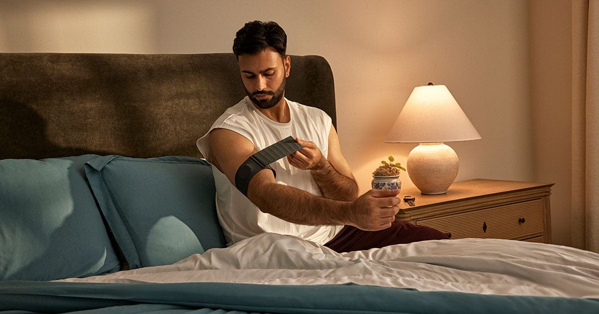גבר עונד את רצועת הניטור Garmin Index Sleep Monitor על הזרוע בחדר שינה (מקור יח"צ)