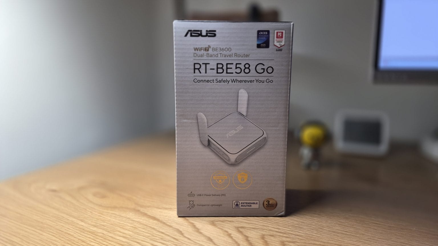 ASUS RT-BE58 Go - אריזת נתב נסיעות ASUS RT-BE58 Go בתקן WiFi 7 BE3600 על שולחן עץ