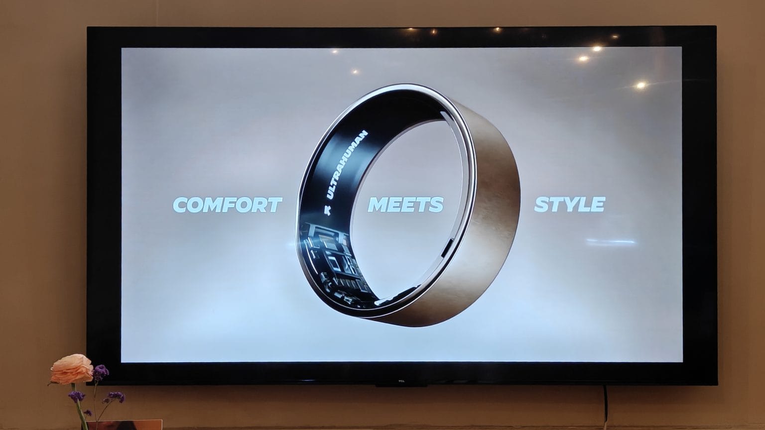 Ultrahuman Ring Air - הטבעת החכמה מוצגת על גבי מסך טלוויזיה עם הכיתוב COMFORT MEETS STYLE, כשהיא חושפת את החיישנים הפנימיים והלוגו.