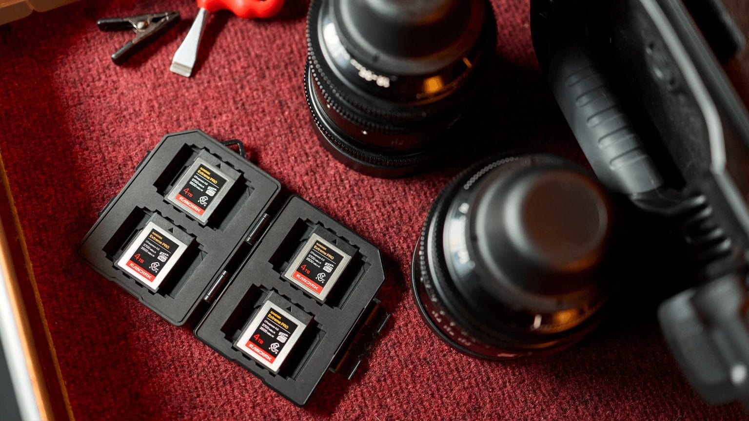 SanDisk CFexpress 4.0 - ארבעה כרטיסי זיכרון SanDisk Extreme PRO CFexpress 4.0 בנפח 4TB מונחים במארז קשיח לצד עדשות צילום מקצועיות