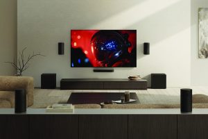 Sony BRAVIA True RGB - תצוגת מערכת קולנוע ביתי הכוללת מסך, מקרן קול, סאבוופרים ורמקולים היקפיים בסלון.