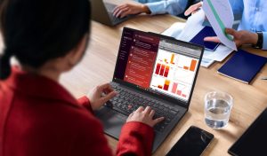 ThinkPad X13 Gen 7 And L Series - אישה עובדת על מחשב נייד בסביבת משרד שיתופית עם תוכנות נתונים פתוחות