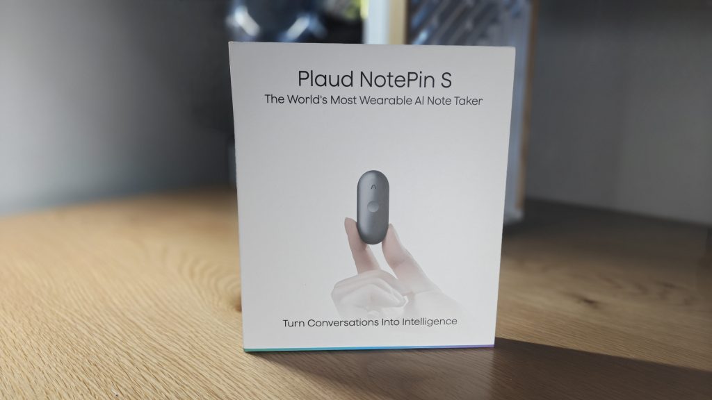 Plaud NotePin S - אריזת הקרטון הקדמית של מכשיר ההקלטה מונחת על שולחן עץ