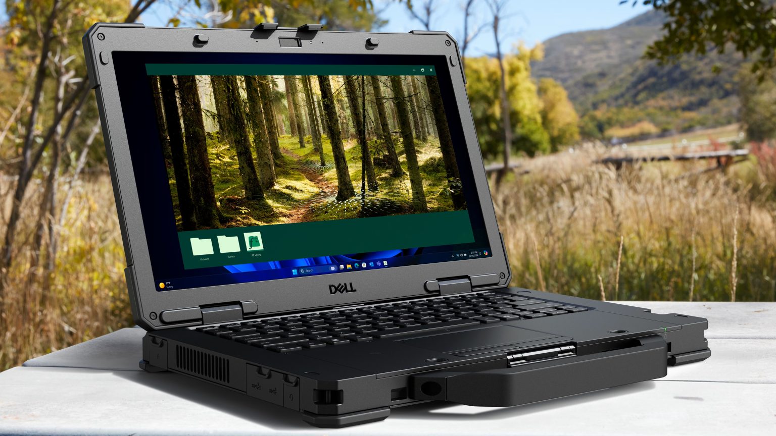 Dell Pro Rugged - מחשב נייד מוקשח פתוח עם ידית נשיאה על רקע נוף טבע