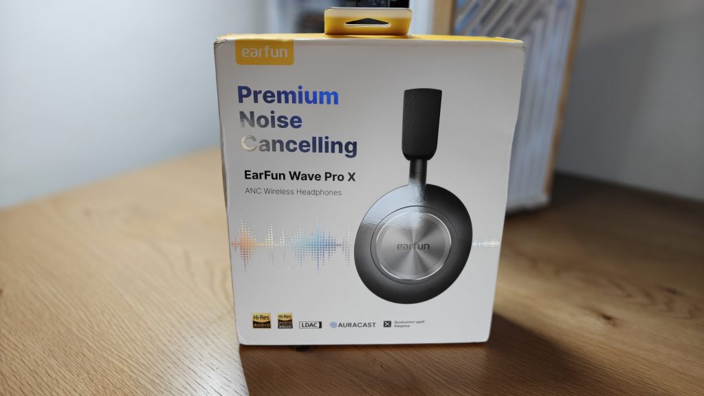 Earfun Wave X Pro - קופסת המוצר של האוזניות מונחת על שולחן עץ